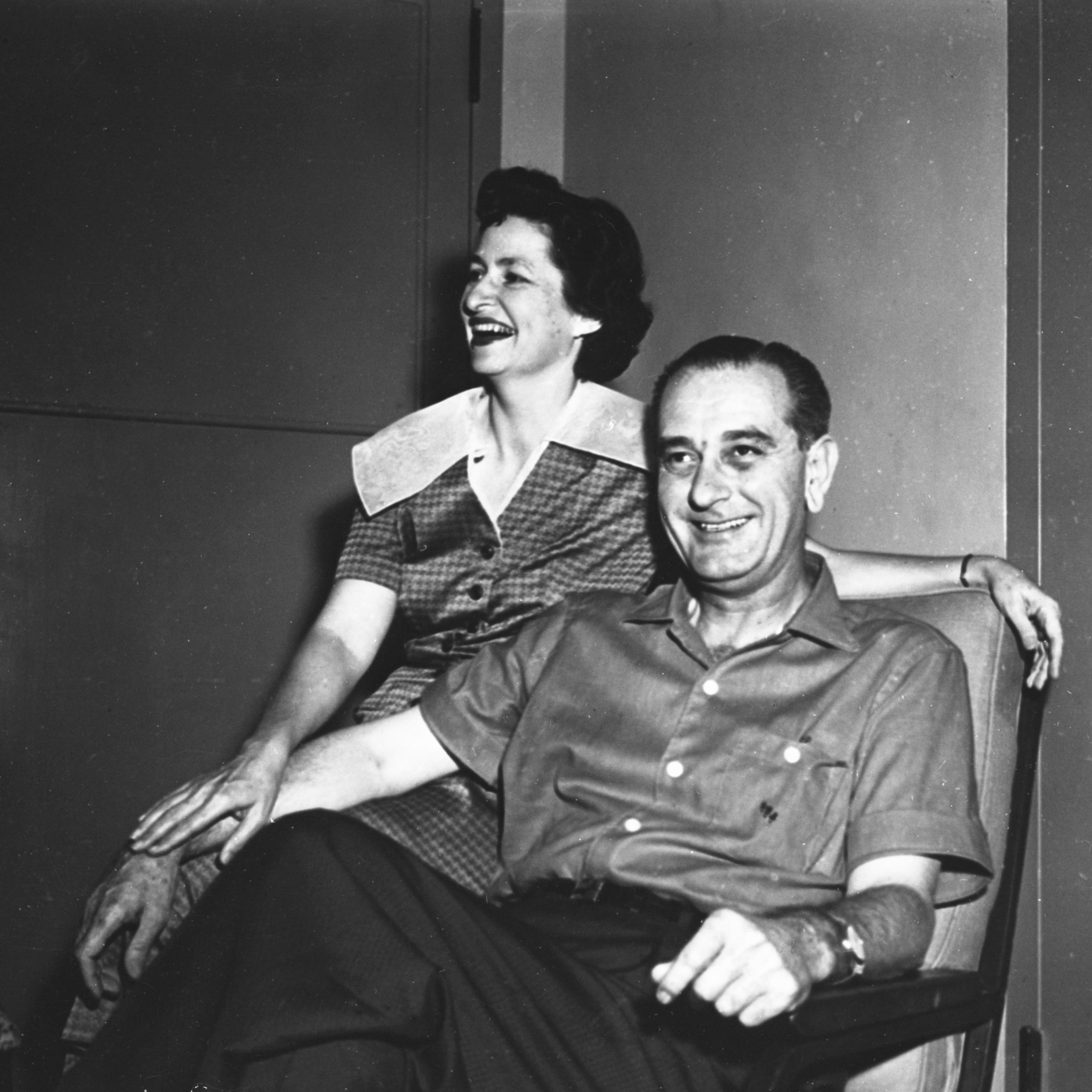Sen. Lyndon B. Johnson sitting in a chair, Lady Bird Johnson sitting on arm of the chair, smiling for the camera